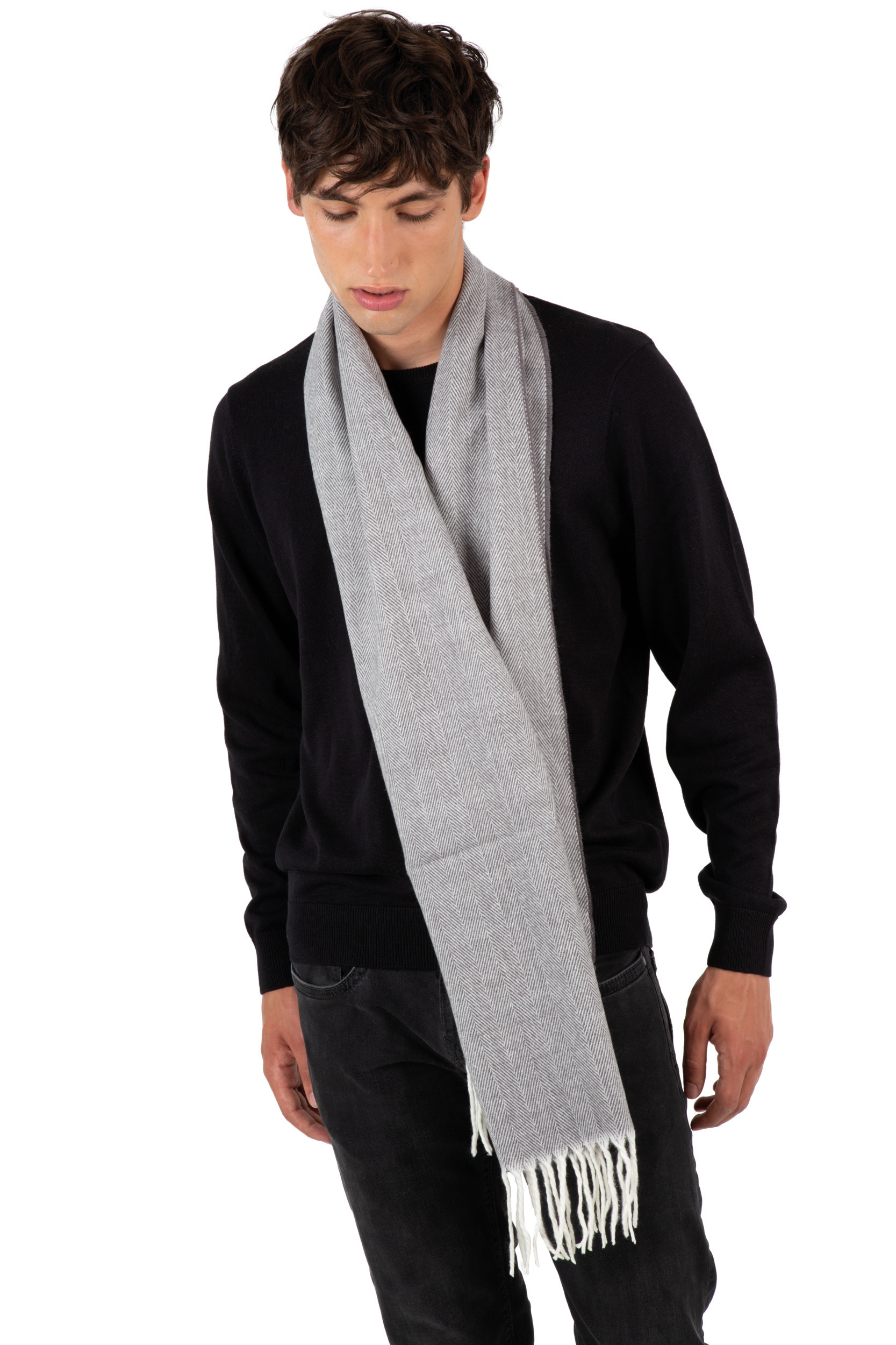 Hombre joven con jersey negro y bufanda gris colgando sobre fondo blanco