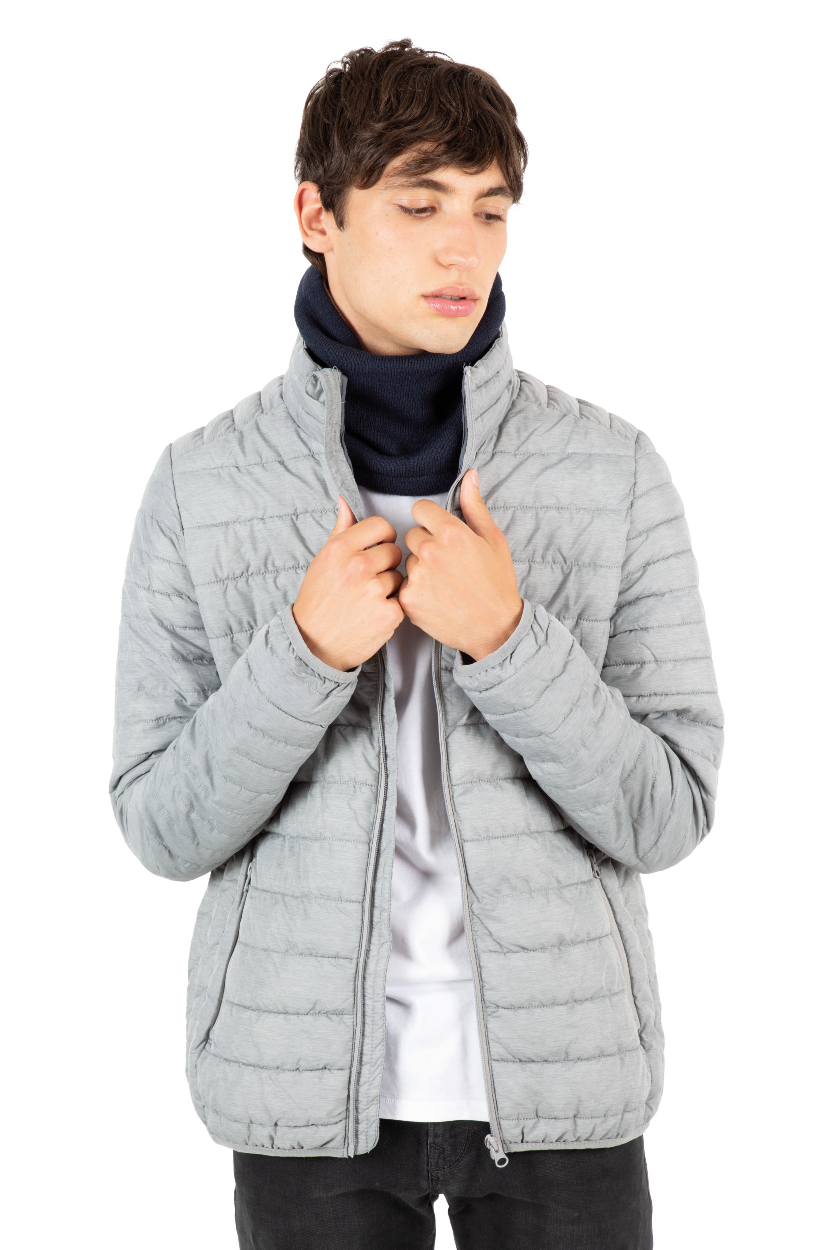 Hombre joven con chaqueta acolchada gris y braga de cuello azul marino sobre fondo blanco