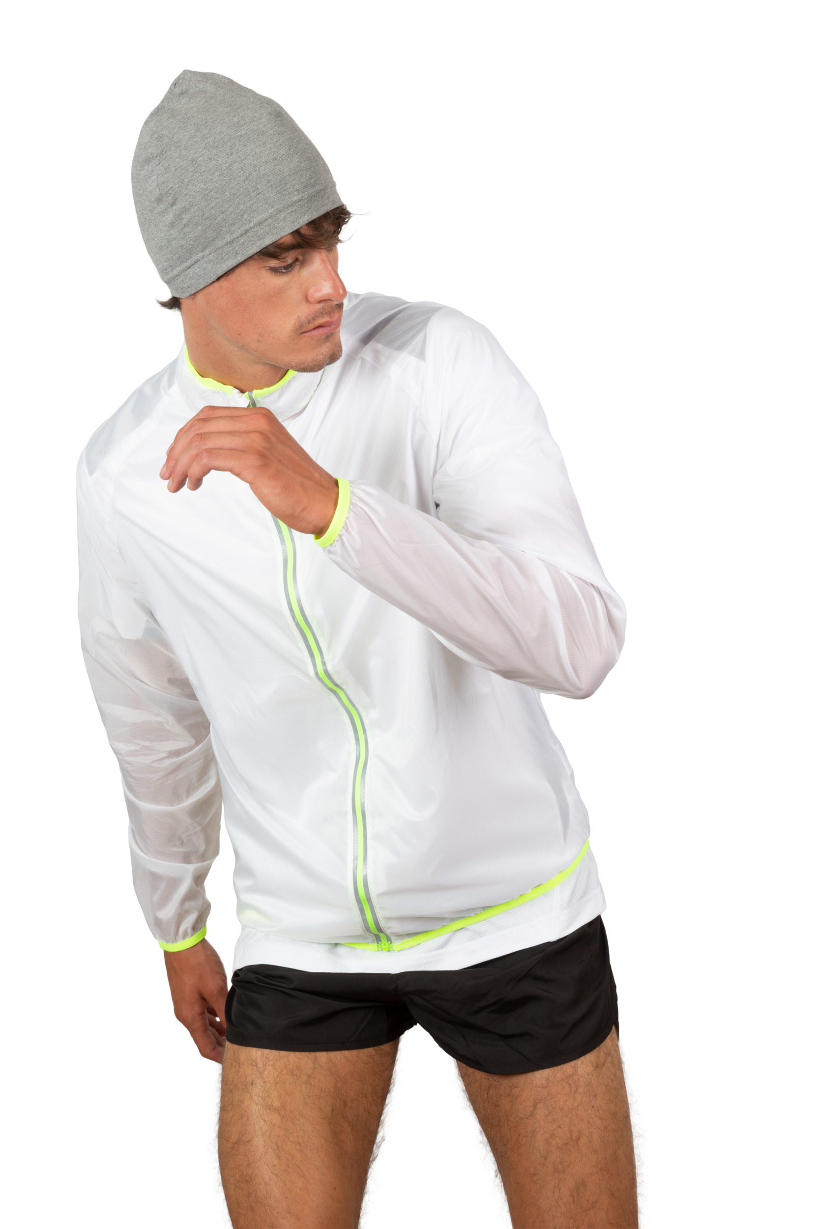 Hombre con chaqueta deportiva blanca translúcida de cremallera reflectante, shorts negros y gorro gris preparándose para correr