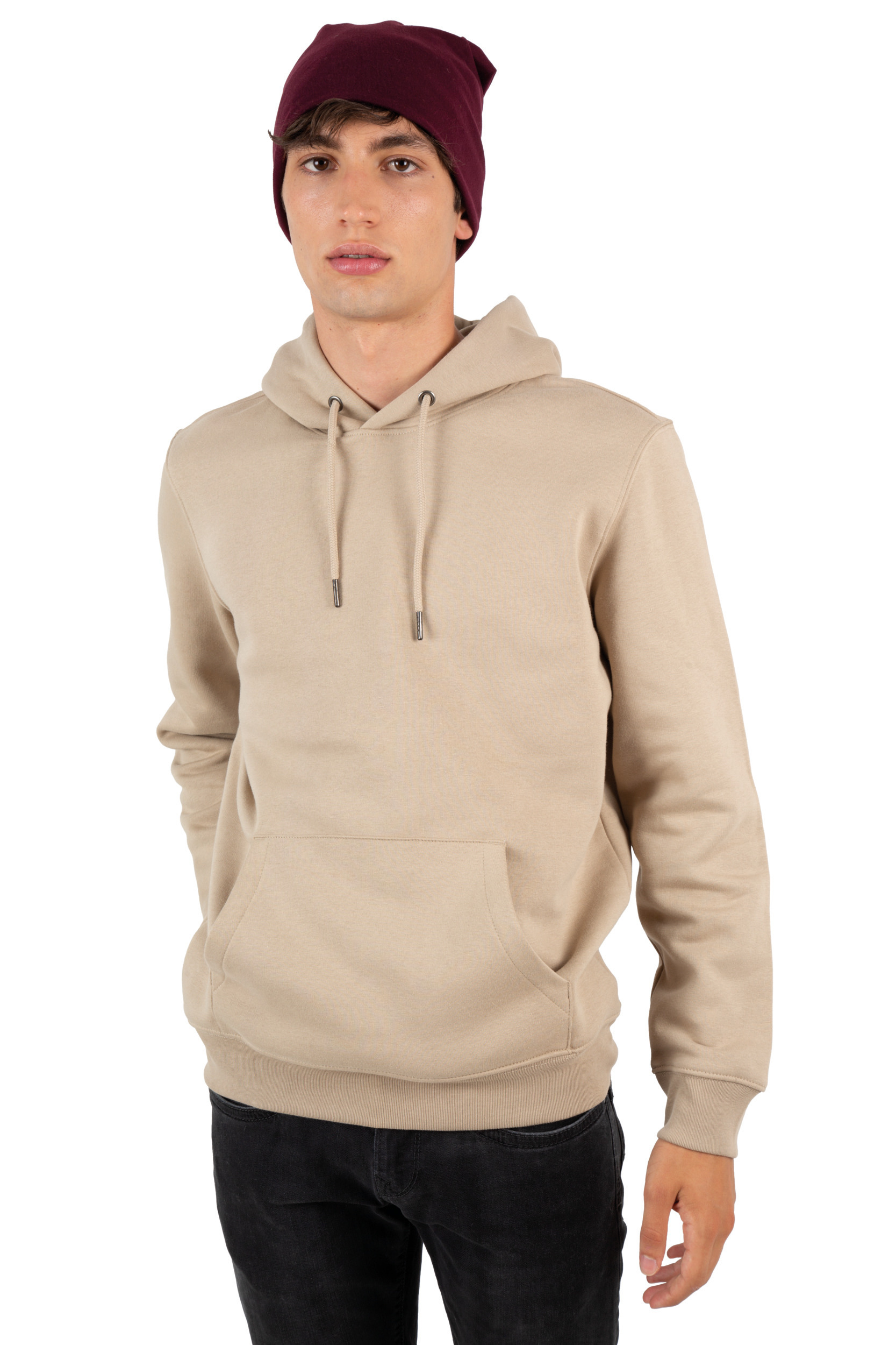 Hombre joven con sudadera beige con capucha y gorro burdeos sobre fondo blanco.