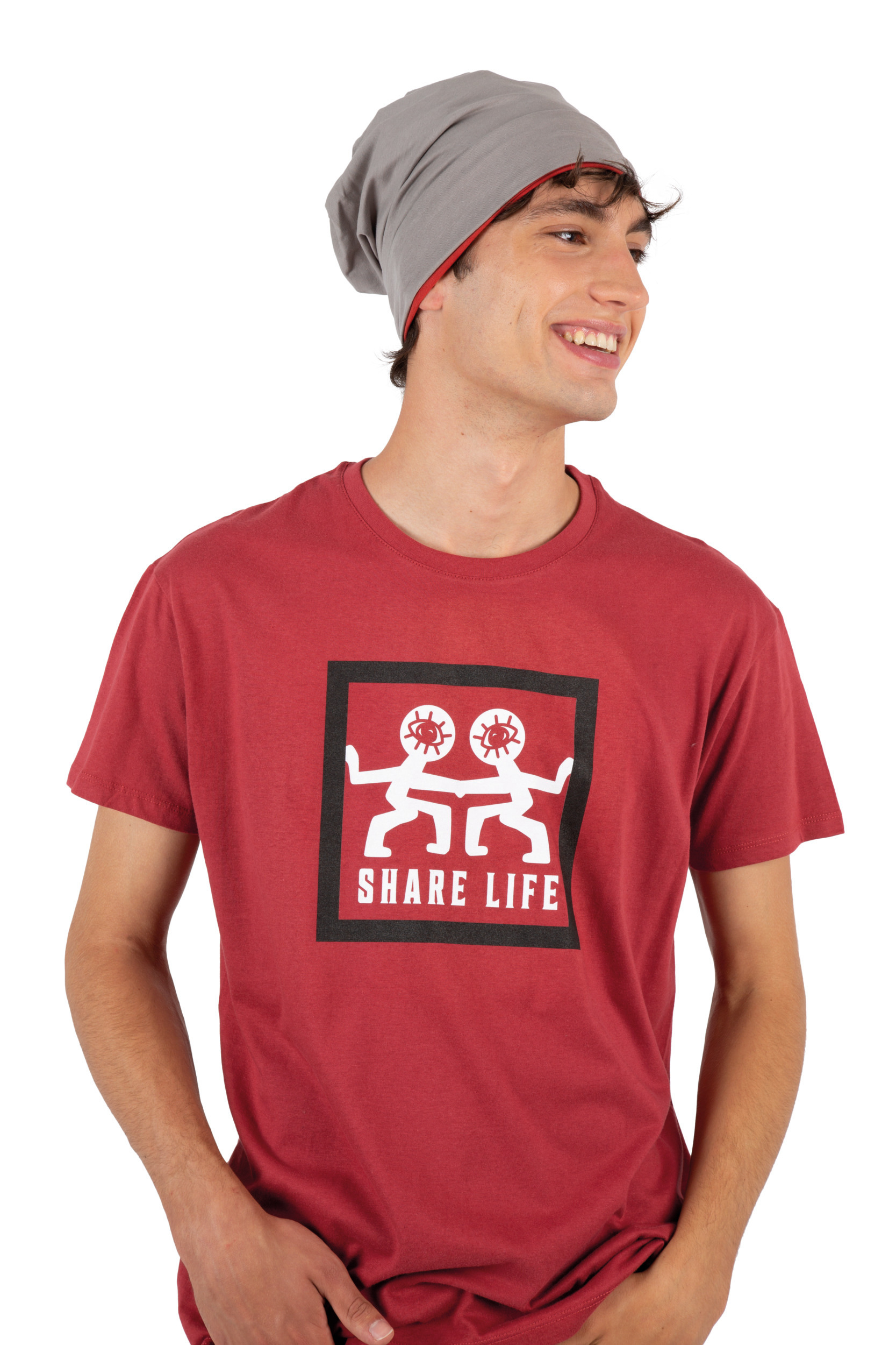 Joven sonriendo con gorro gris y camiseta roja estampada con dos figuras blancas y el texto Share Life