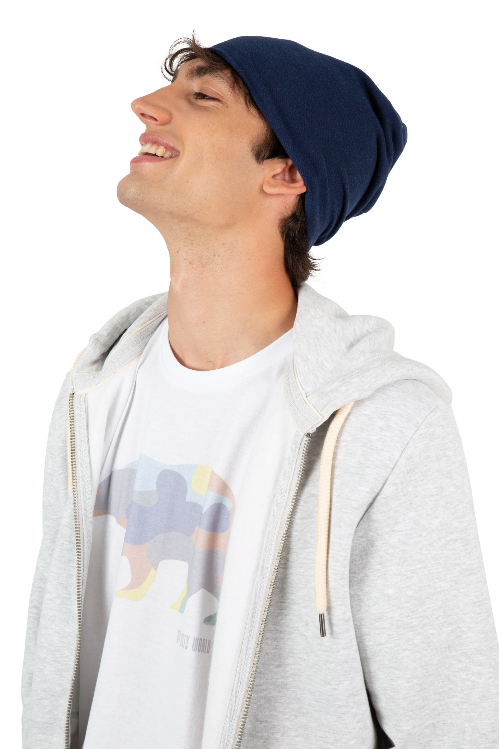 Joven sonriente con gorro azul, sudadera gris abierta y camiseta blanca con estampado de oso multicolor.