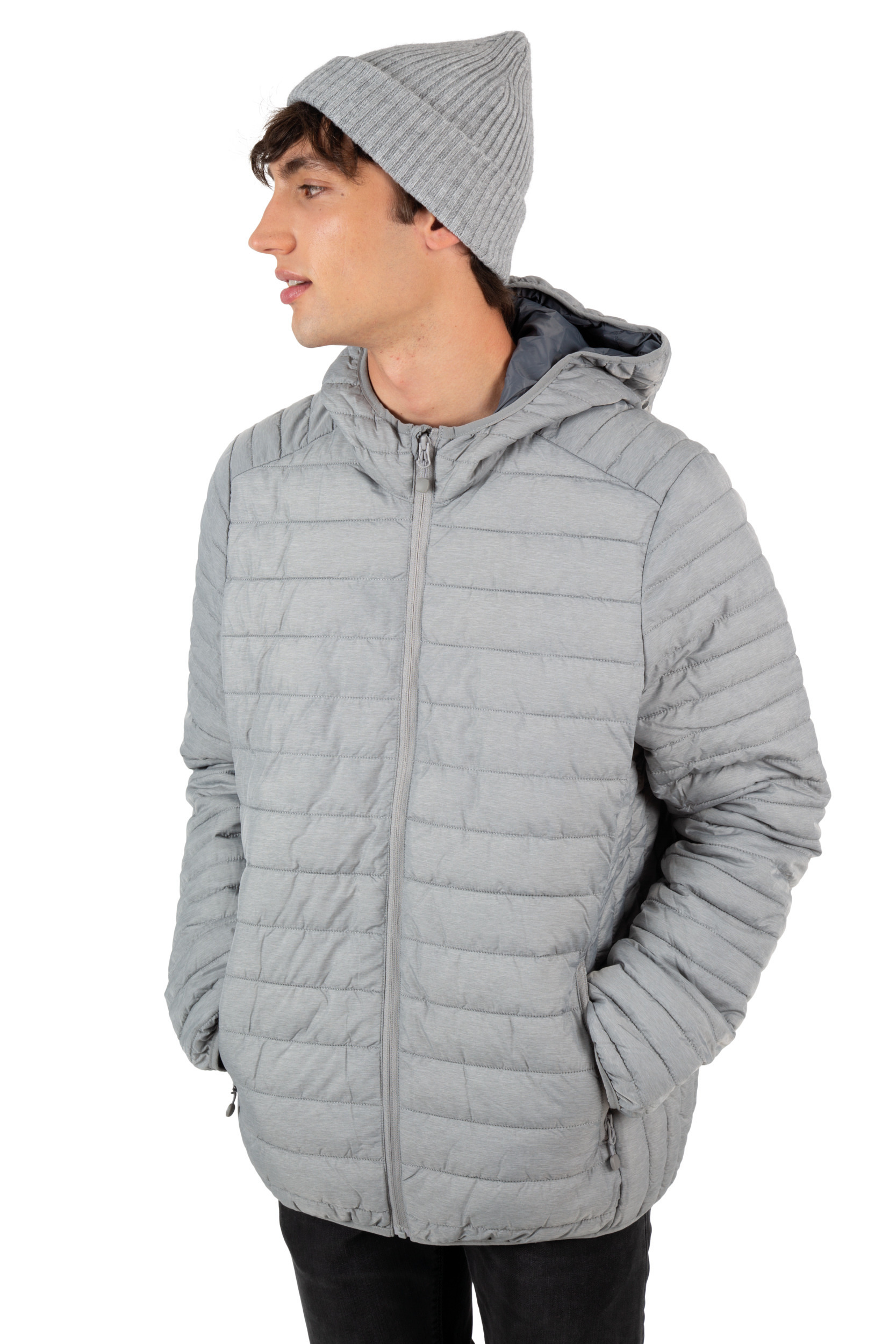Hombre joven de perfil con chaqueta acolchada gris con capucha y gorro de punto mirando hacia la izquierda.
