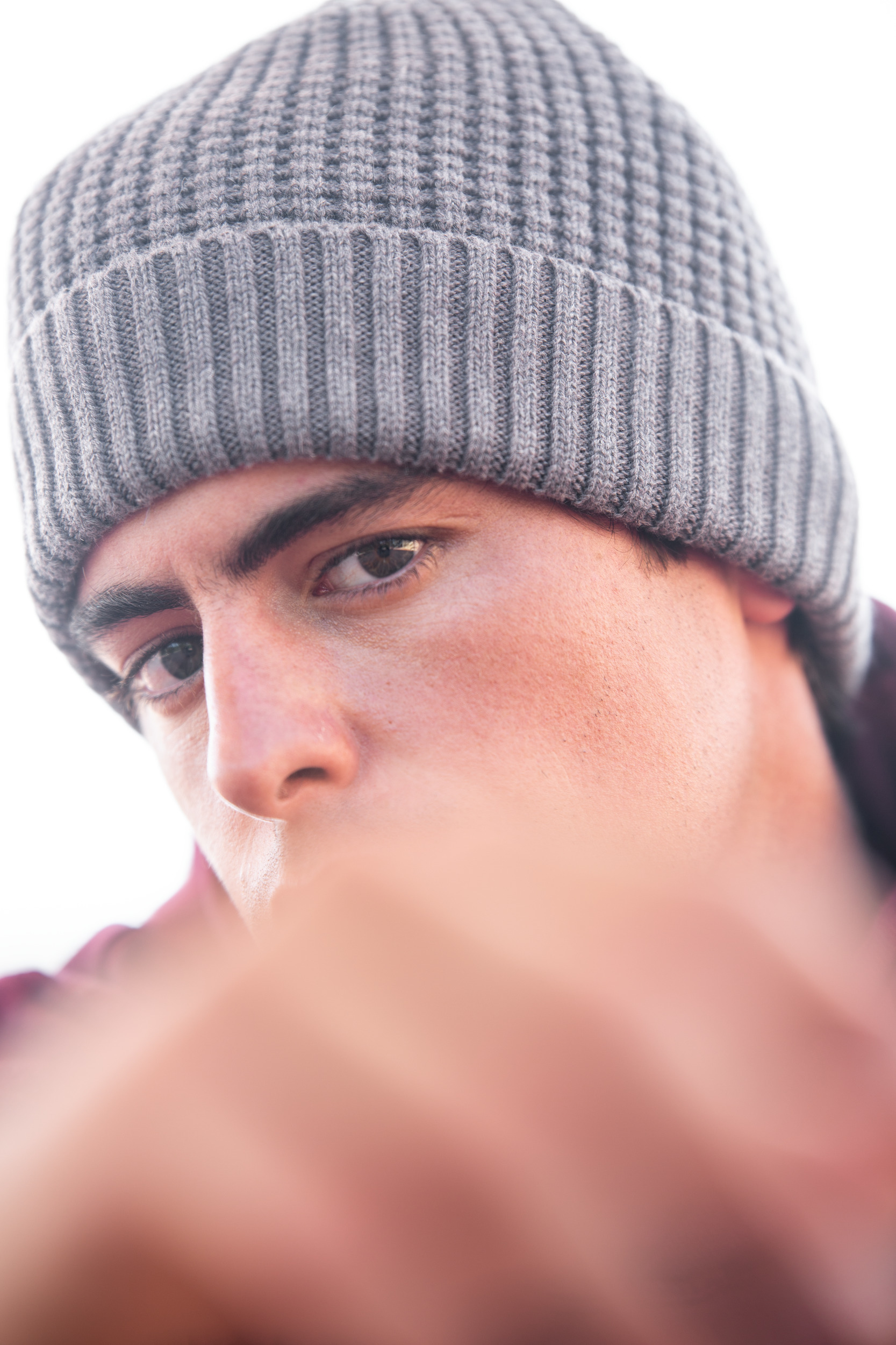 Primer plano de un joven con gorro de punto gris y mirada intensa.