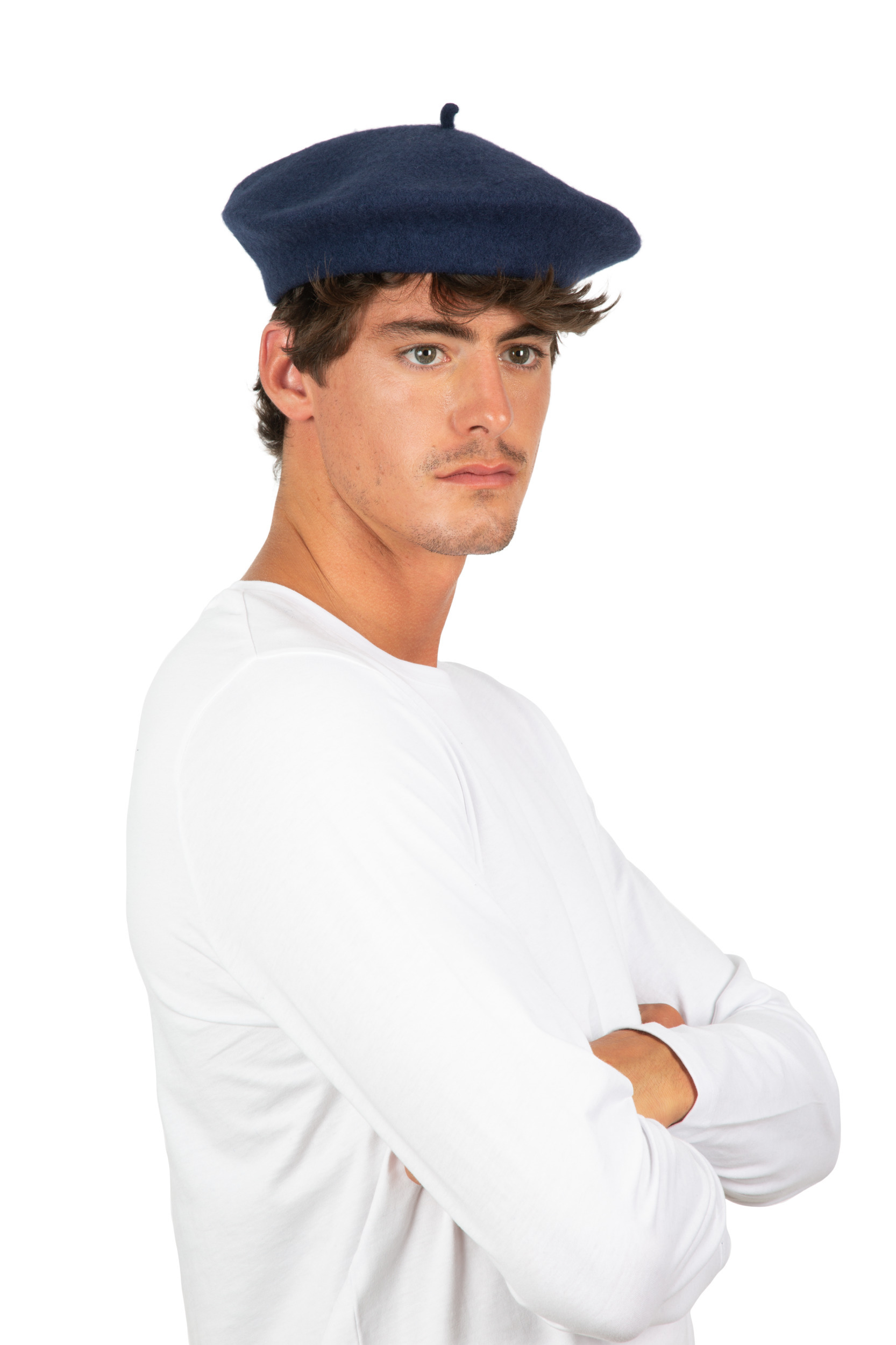hombre joven con boina azul marino y camiseta blanca de manga larga, brazos cruzados sobre fondo blanco