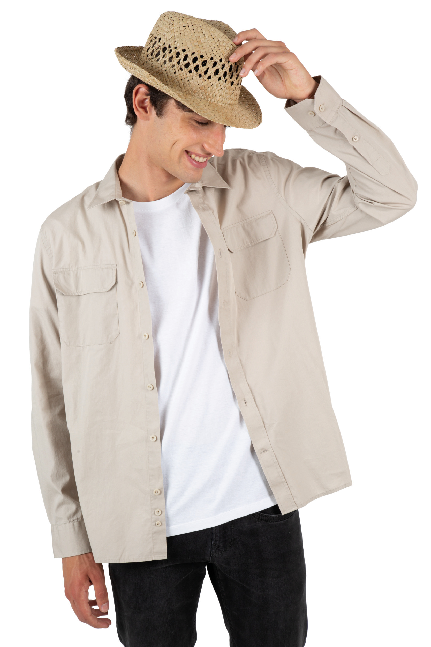 Hombre joven con camisa beige abierta sobre camiseta blanca y sombrero de paja ajustándose el ala.