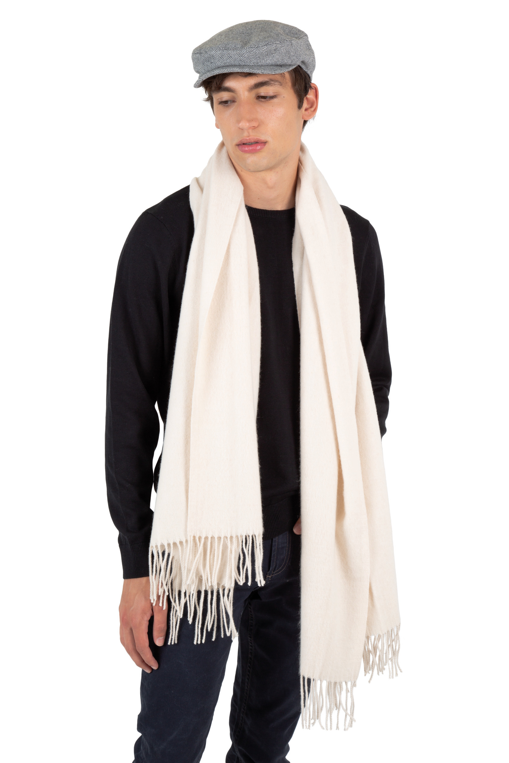 Hombre con gorra plana y bufanda de lana color crema posando sobre fondo blanco