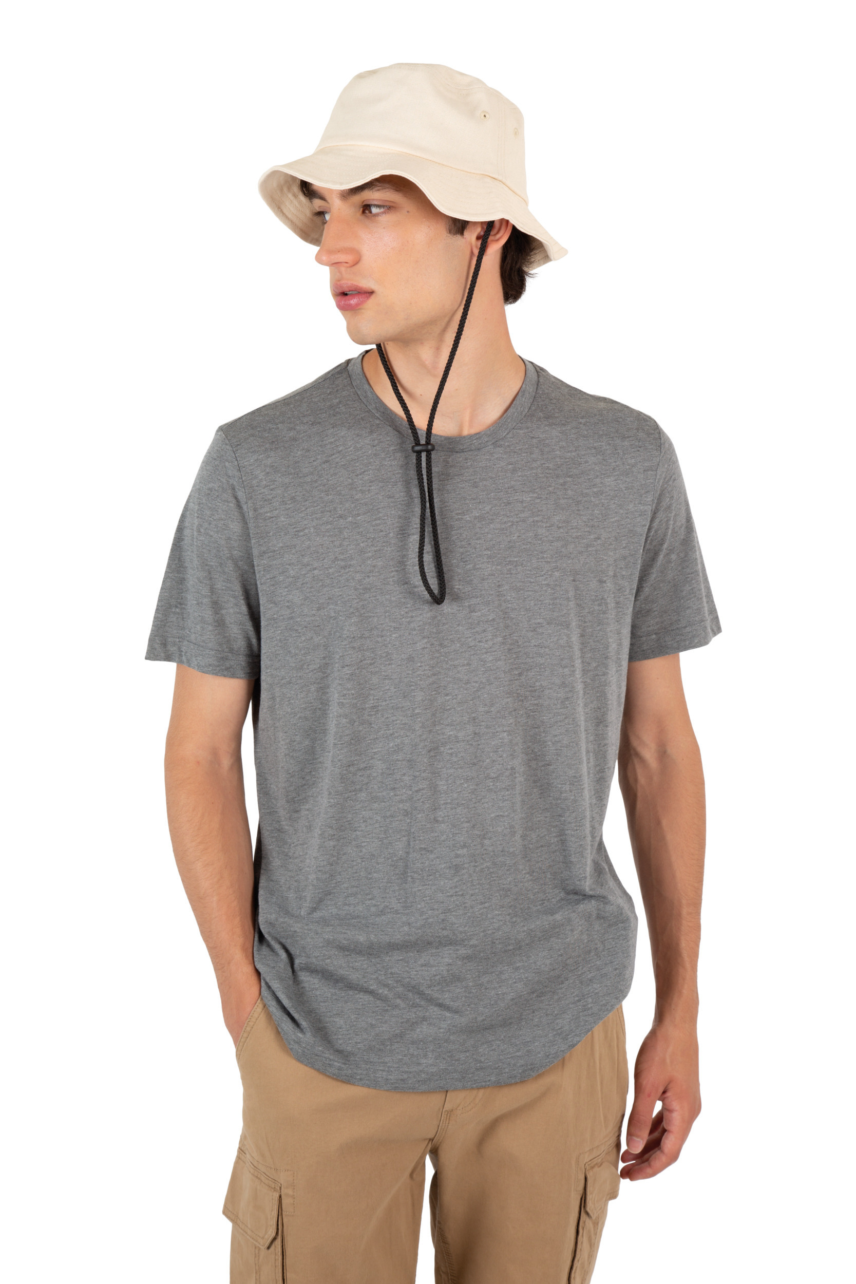 hombre joven con sombrero bucket beige, camiseta gris y pantalones cargo claros sobre fondo blanco