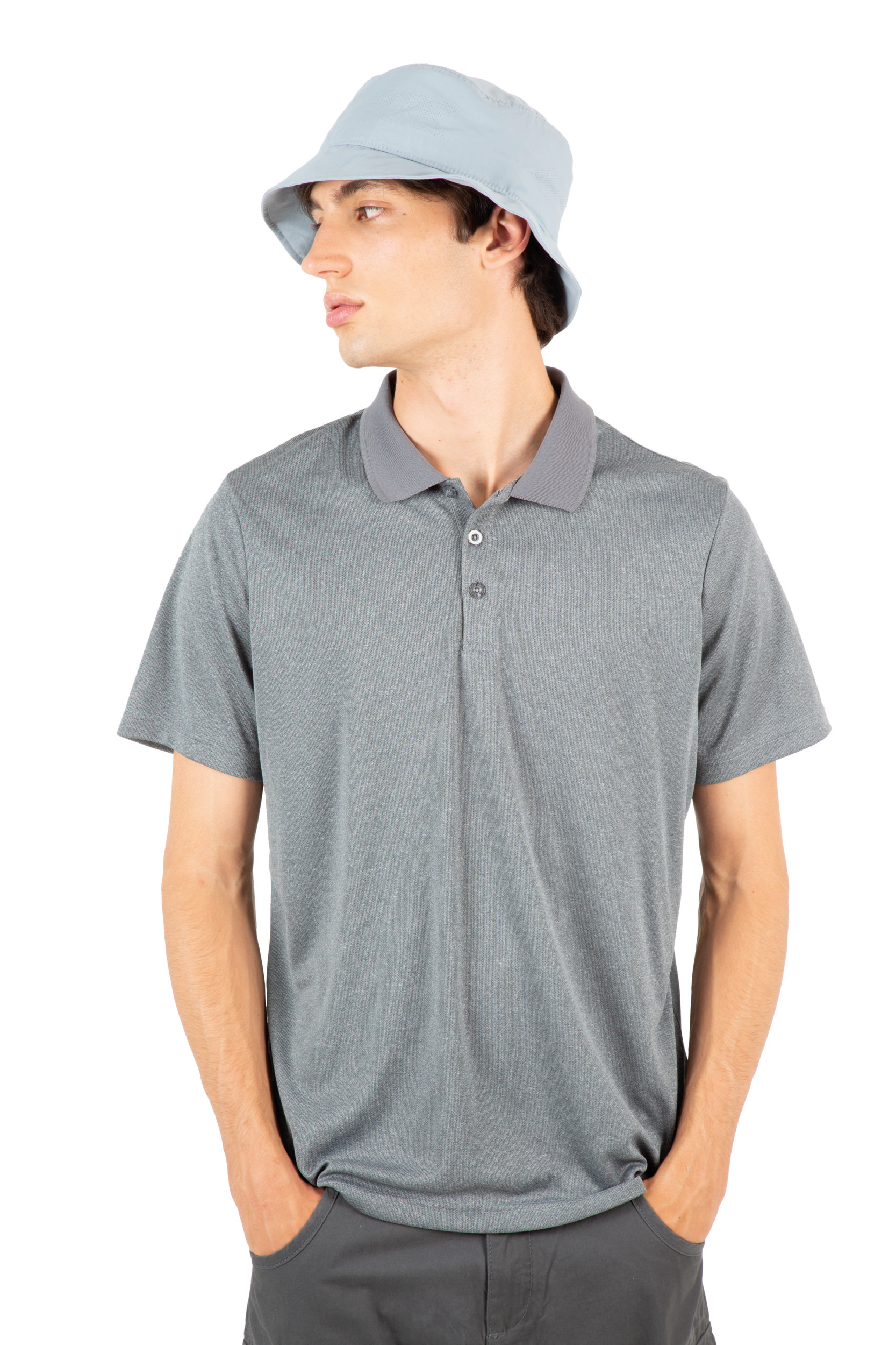 Hombre joven de perfil con polo gris y sombrero tipo pescador azul claro, con las manos en los bolsillos, sobre fondo blanco.