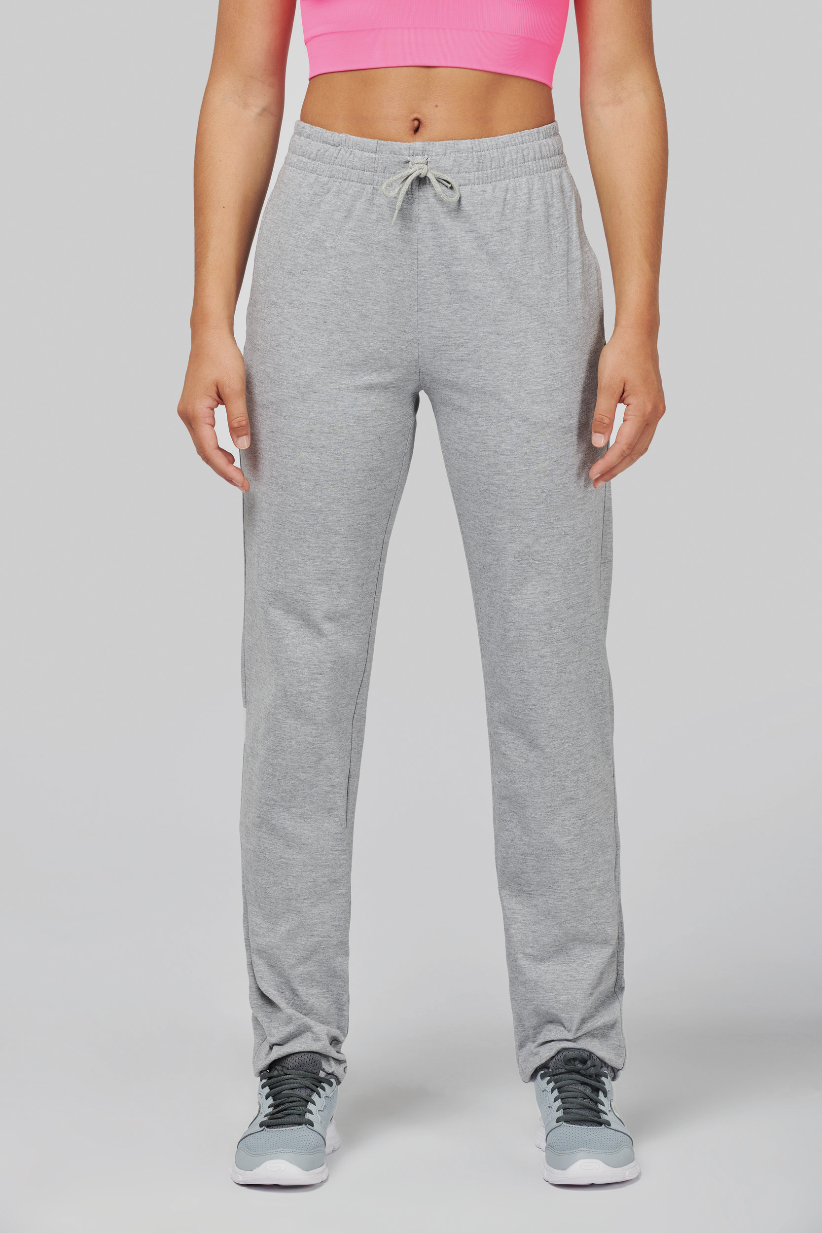 Mujer con pantalones deportivos grises de cintura elástica y cordón y zapatillas deportivas.