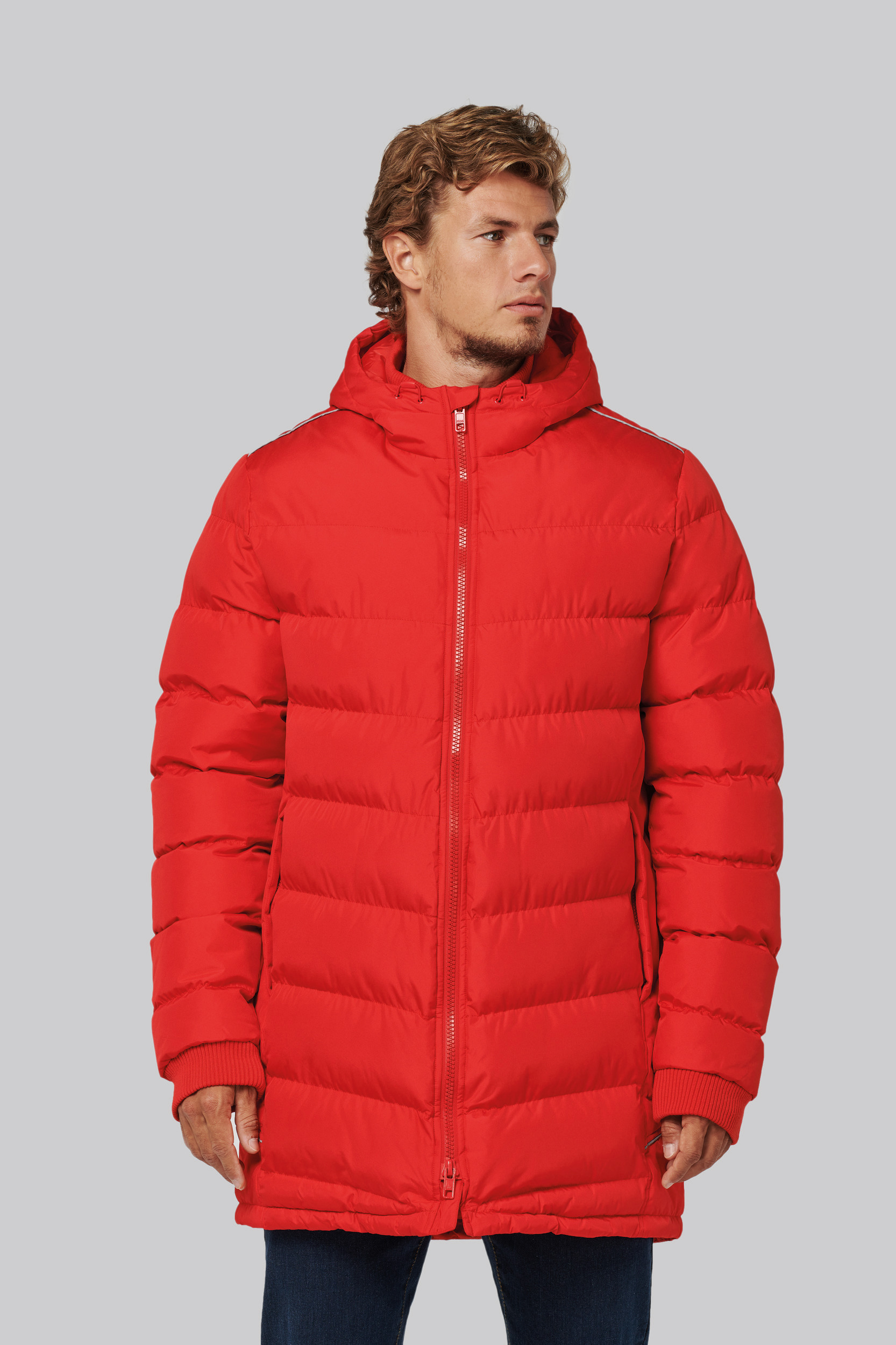 Hombre con abrigo largo acolchado rojo con capucha sobre fondo neutro