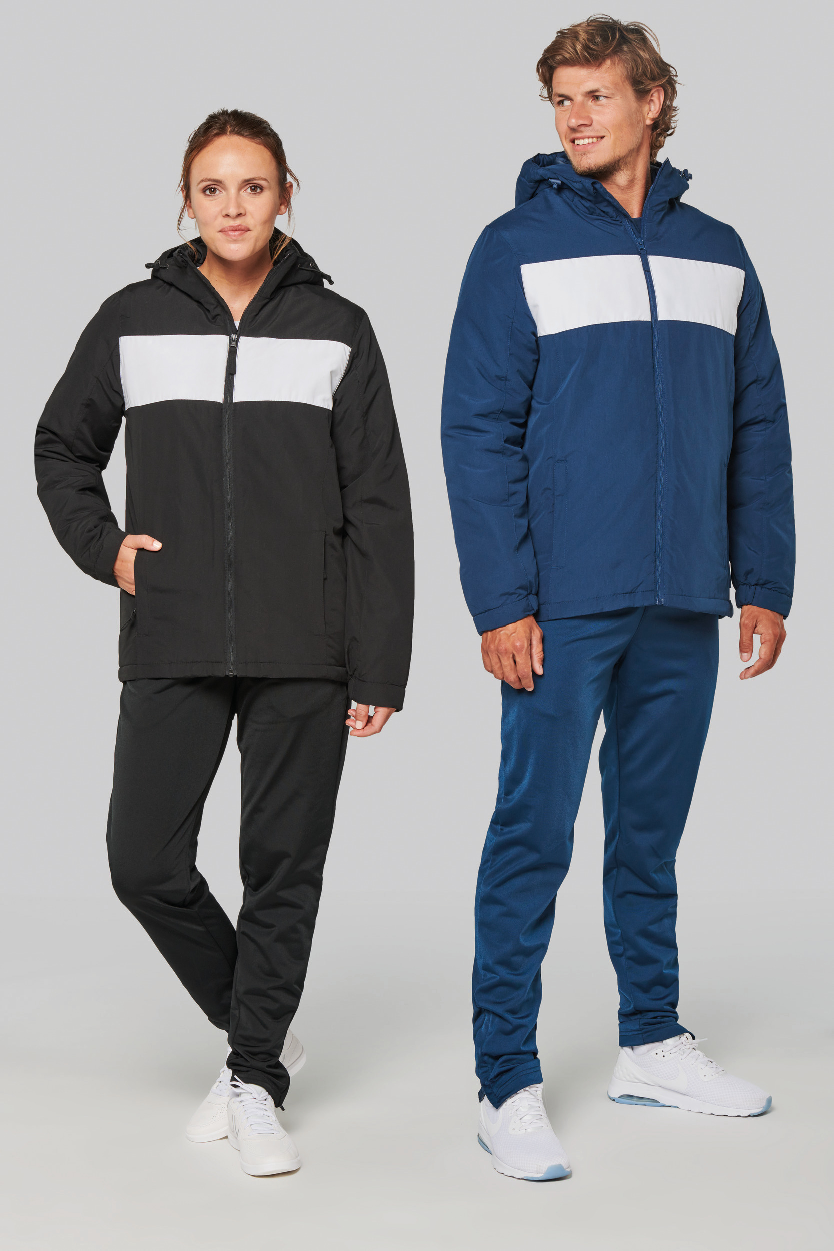 Mujer y hombre posando con chaquetas acolchadas con franja blanca sobre fondo gris claro