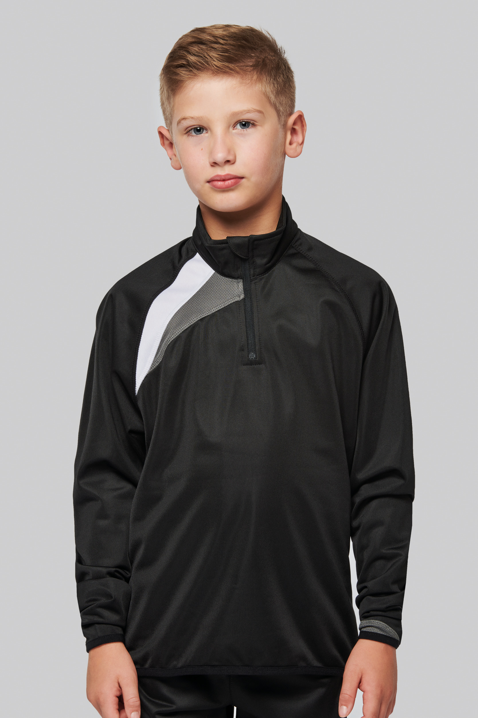 Niño con camiseta deportiva negra de manga larga sobre fondo gris claro