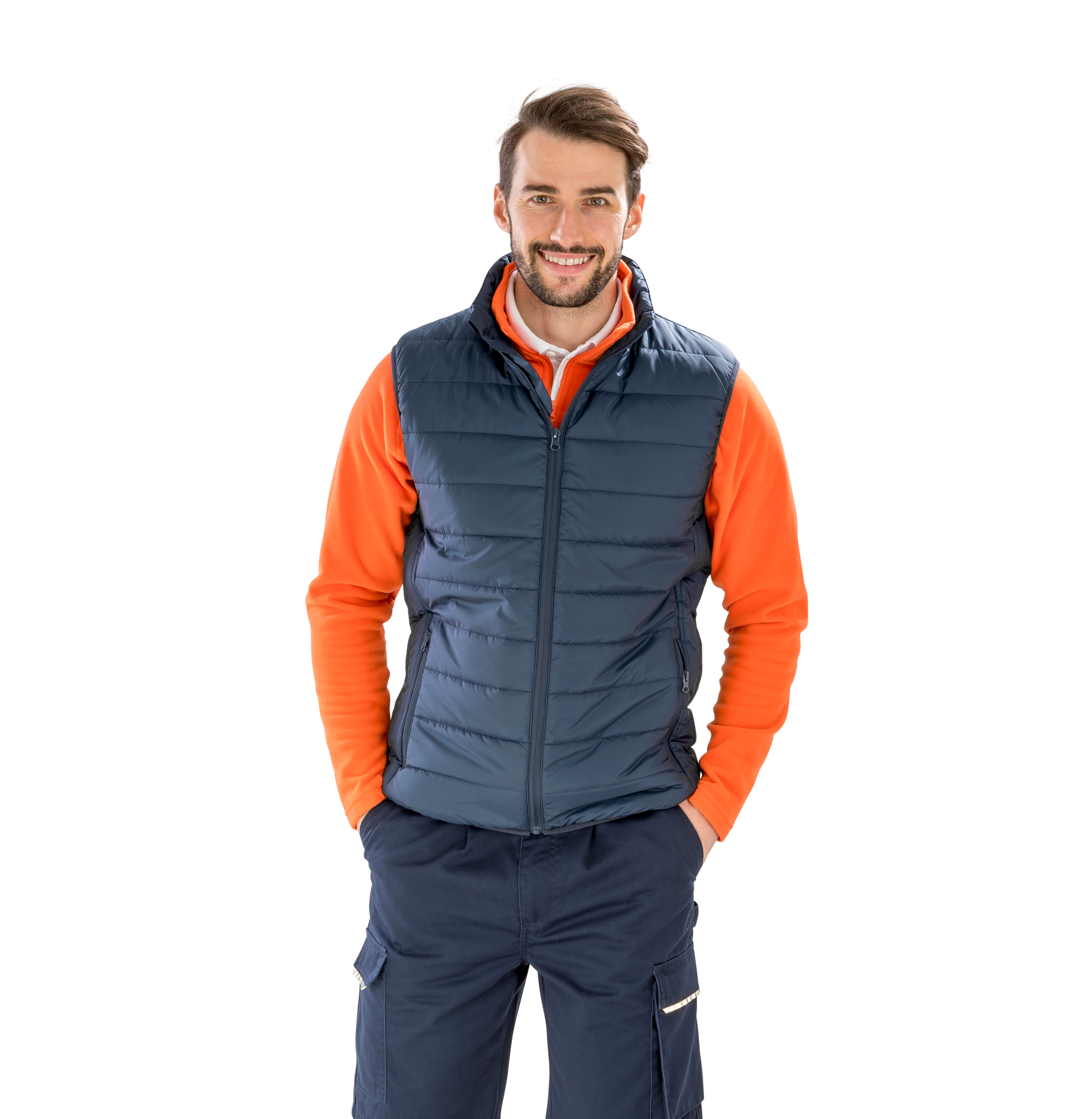 Hombre sonriente con chaleco acolchado azul y camiseta naranja sobre fondo blanco.