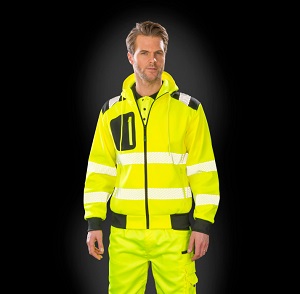 Hombre con chaqueta y pantalón de alta visibilidad amarillo con bandas reflectantes sobre fondo oscuro