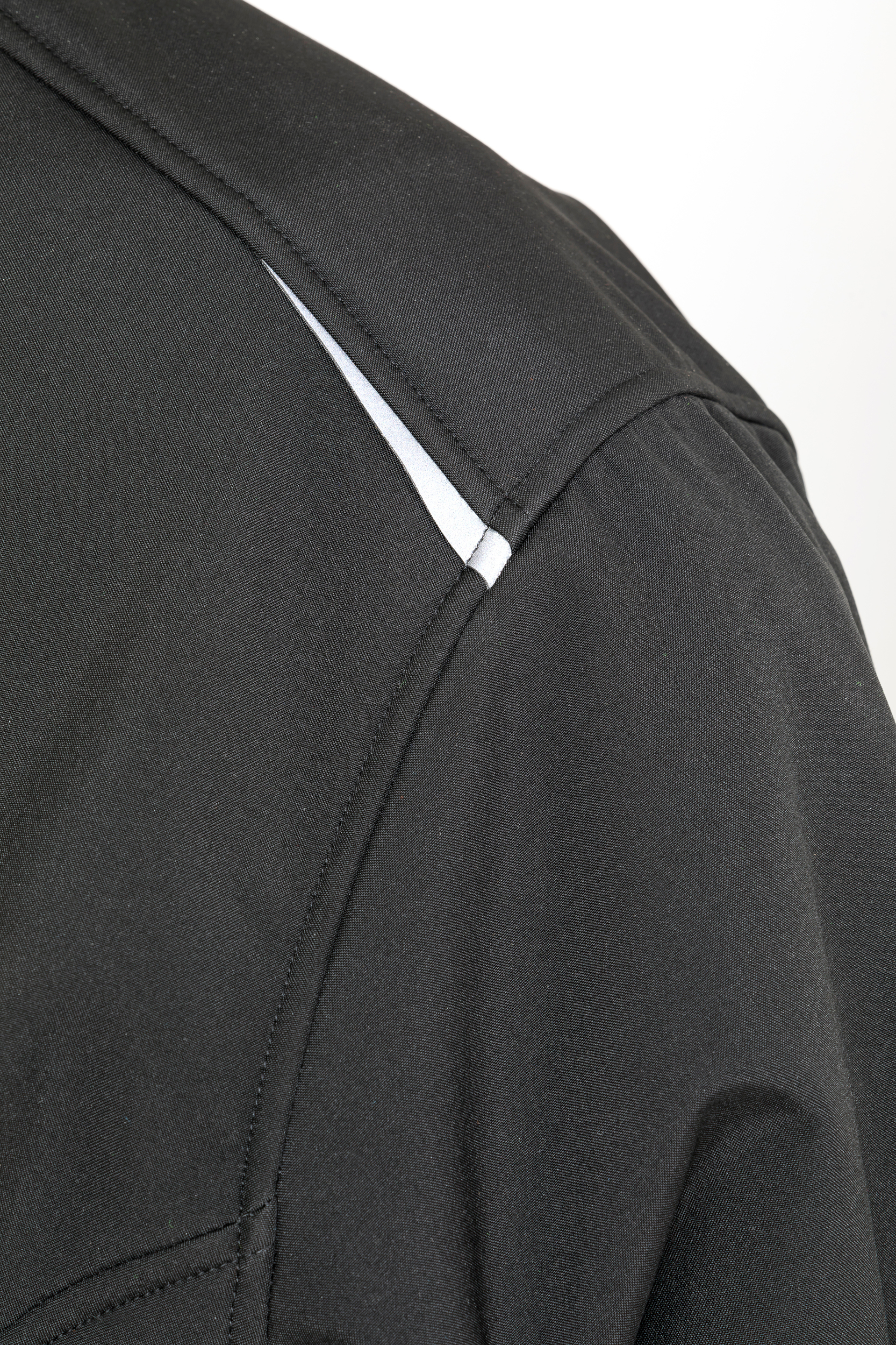 Detalle del hombro de una chaqueta negra con ribete blanco
