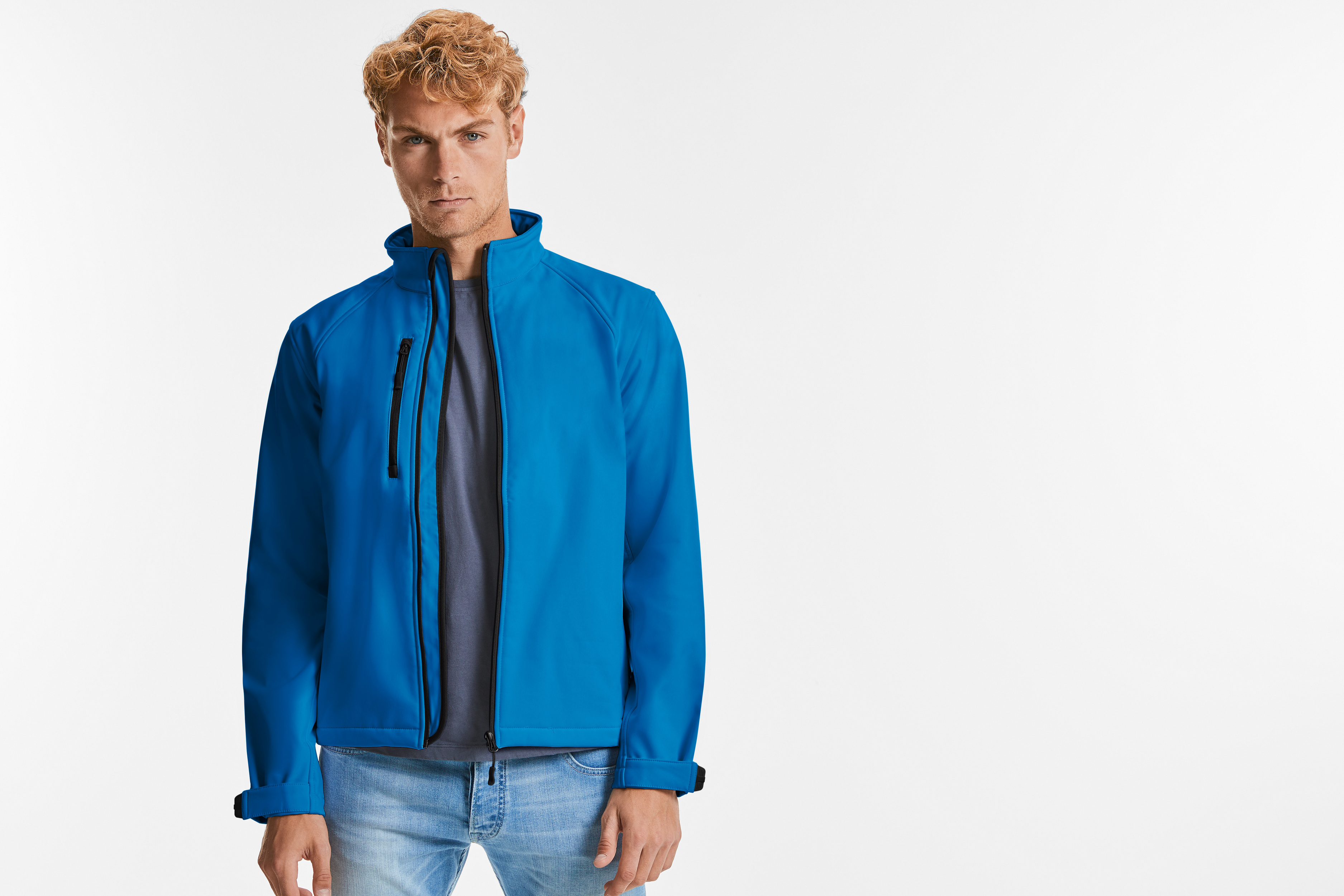 Hombre con chaqueta softshell azul y vaqueros sobre fondo blanco