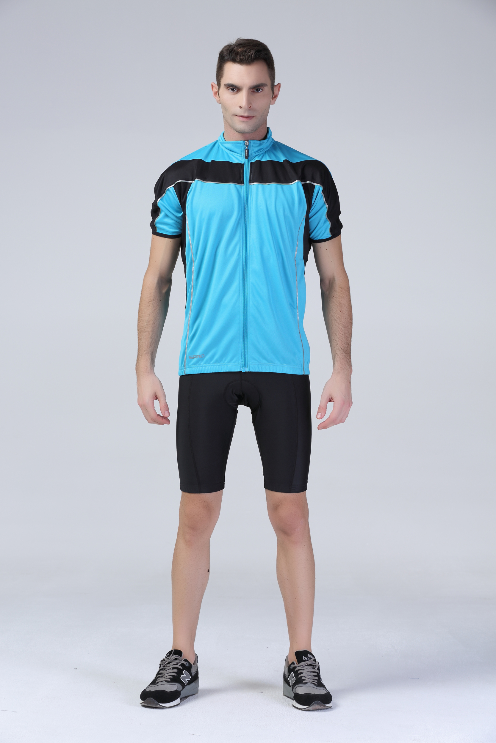 Hombre en fondo neutro vistiendo maillot azul y culotte negro de ciclismo.