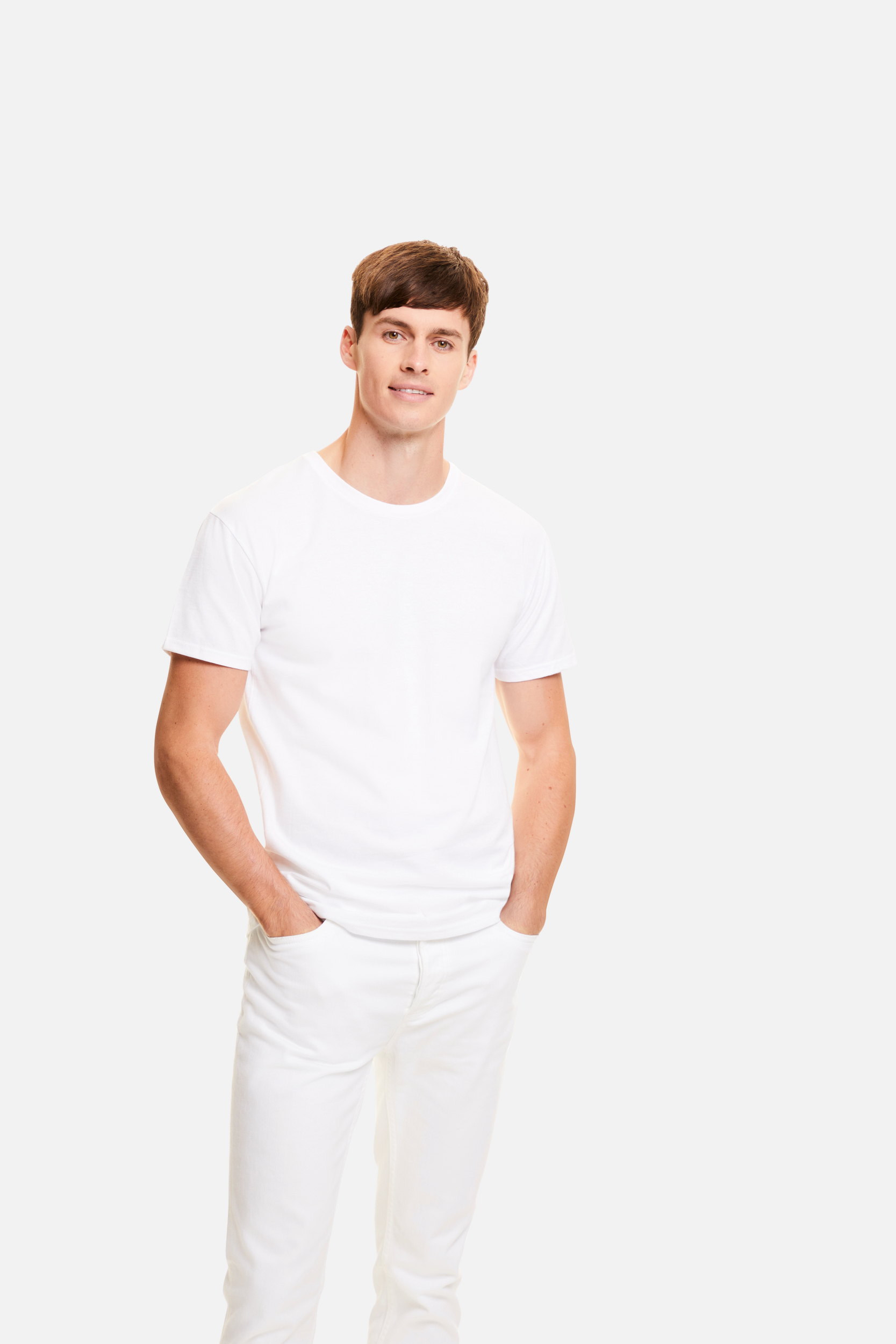 hombre joven de pie con camiseta y pantalones blancos sobre fondo neutro
