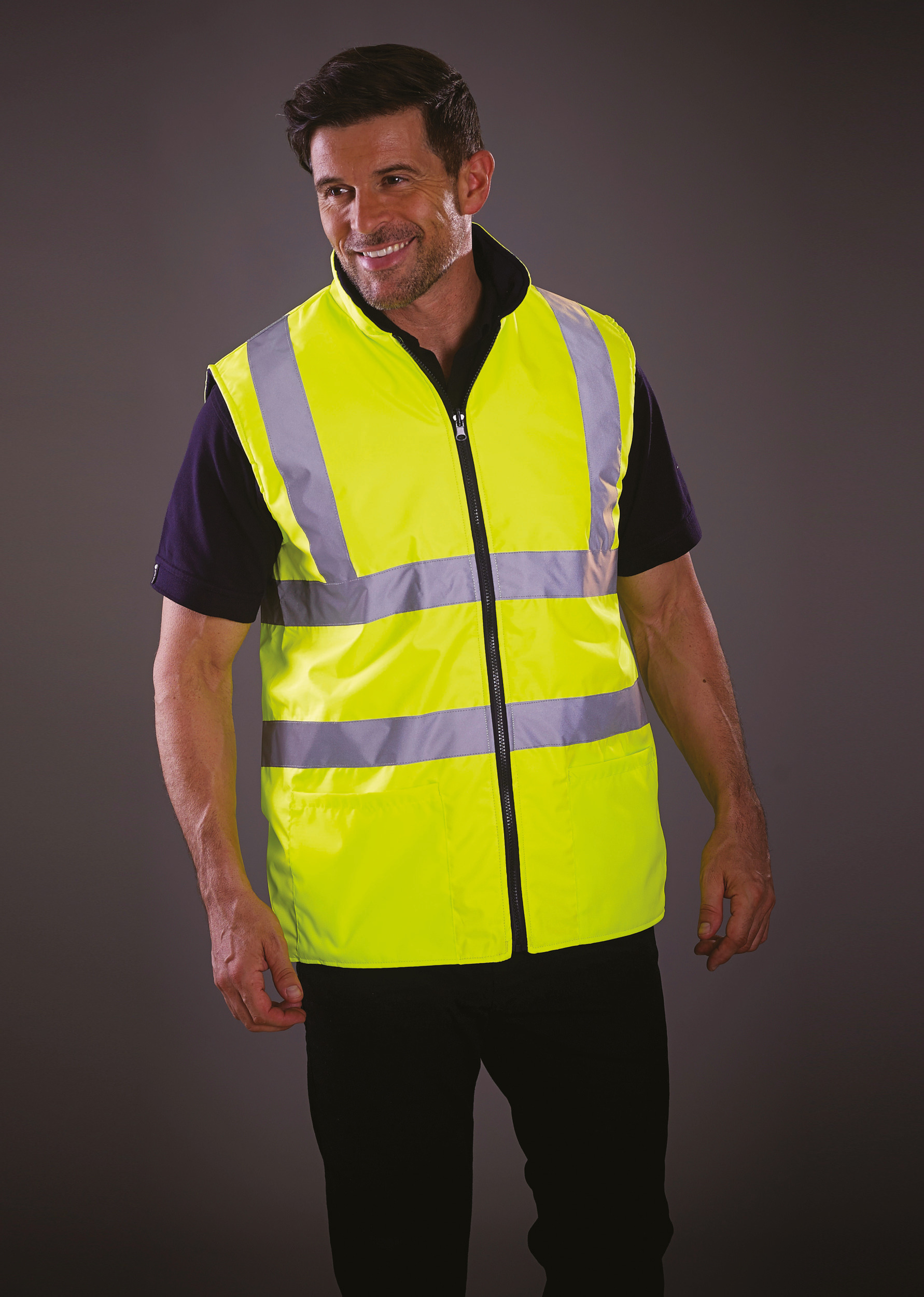 Hombre con chaleco reflectante amarillo de seguridad sobre fondo neutro.