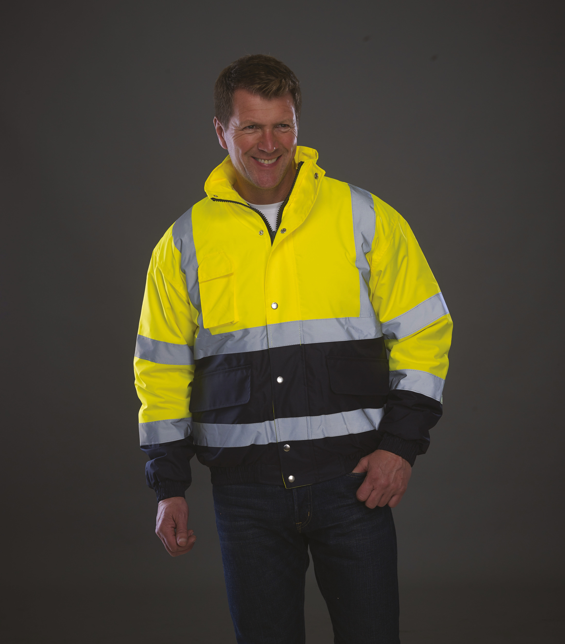 Hombre sonriente con chaqueta de alta visibilidad reflectante sobre fondo oscuro