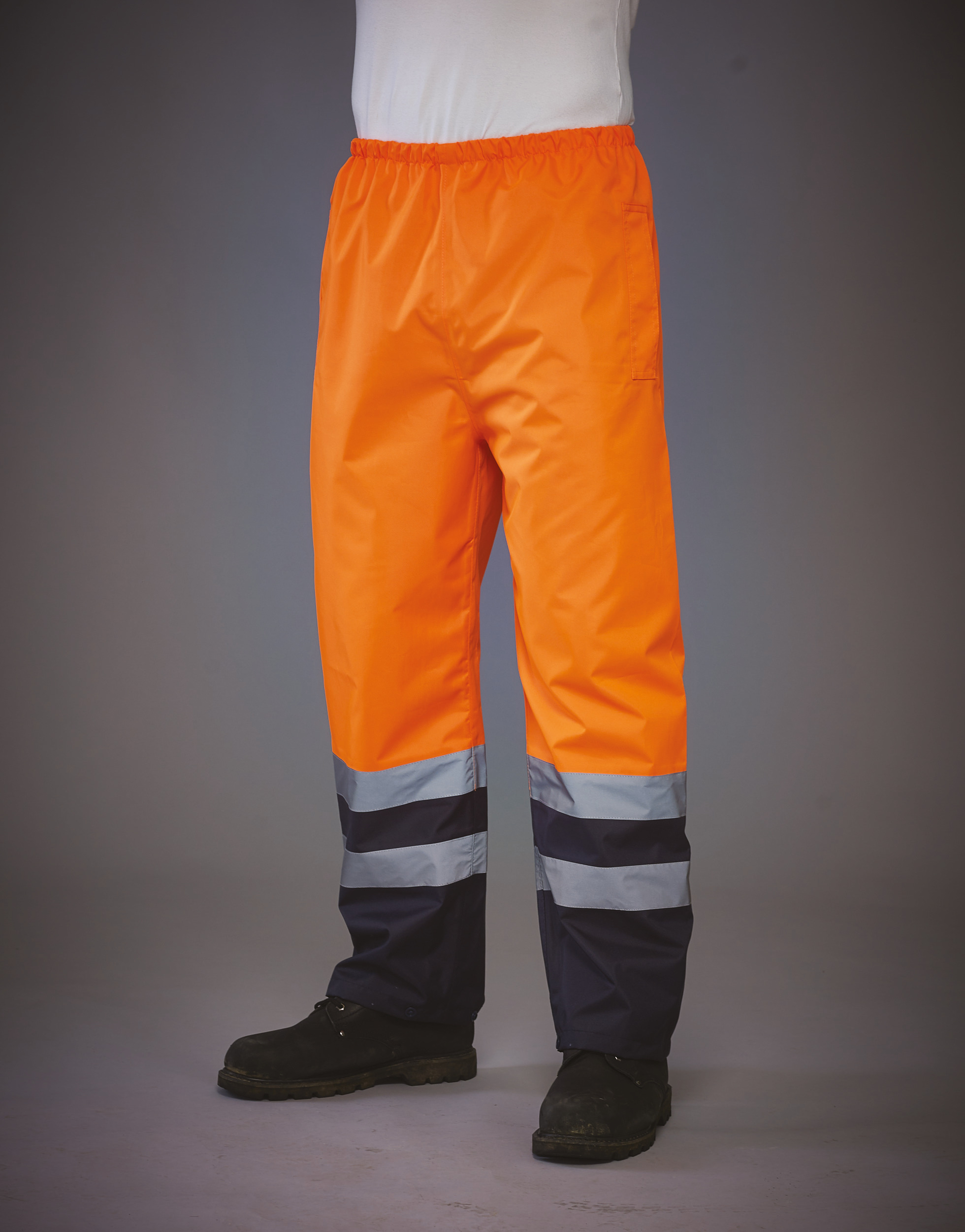 Pantalones de alta visibilidad naranjas con franjas reflectantes y botas de seguridad