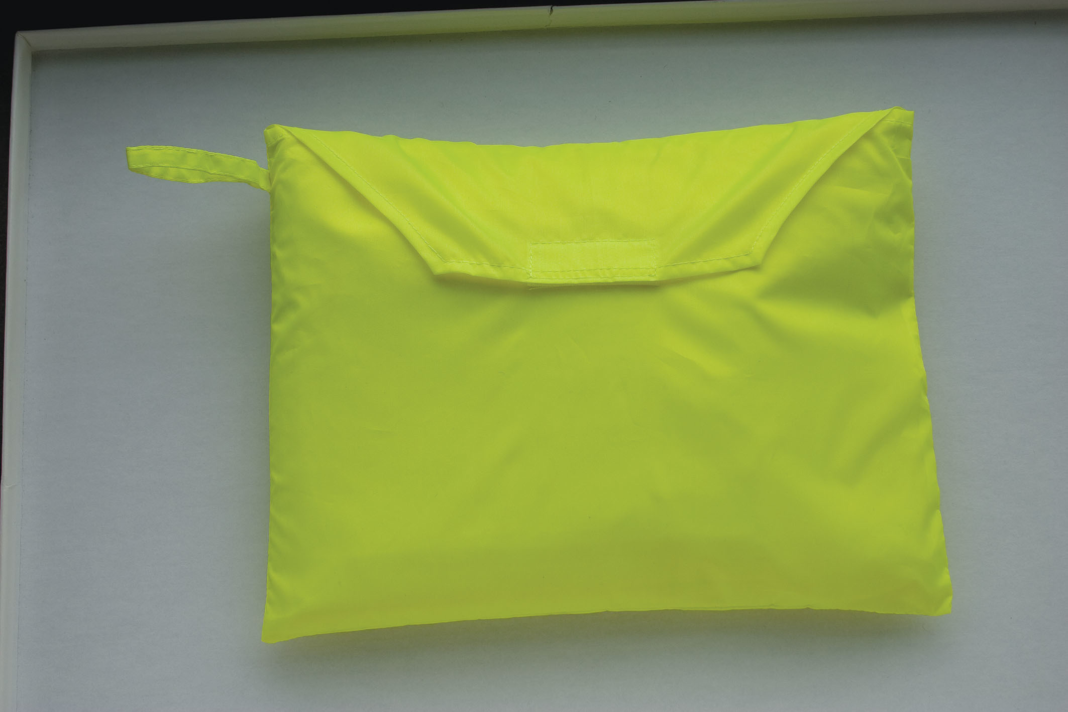 bolsa acolchada amarilla con solapa y asa sobre fondo gris claro