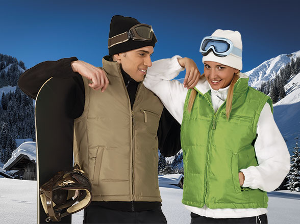 pareja con ropa de nieve y gafas de esquí posando junto a una tabla de snowboard en un paisaje montañoso nevado