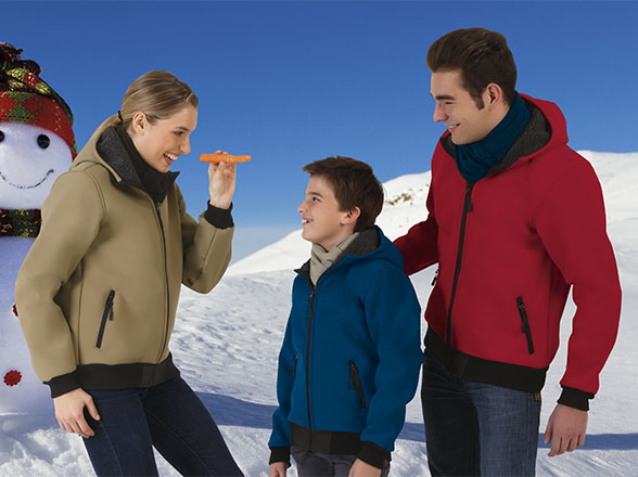Familia sonriente colocando la nariz de zanahoria a un muñeco de nieve en un paisaje invernal de montaña
