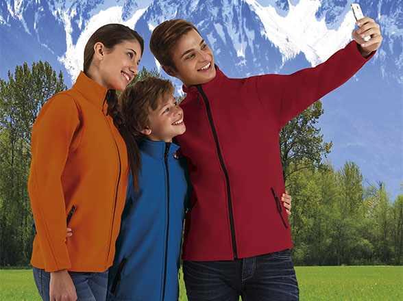 Familia con chaquetas de colores haciéndose un selfie ante un paisaje de montaña nevada