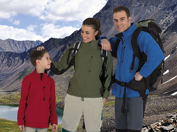 Familia con chaquetas y mochilas posando en un paisaje montañoso junto a un lago
