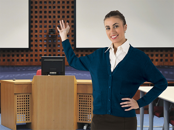 mujer sonriente señalando un atril en una sala de conferencias moderna