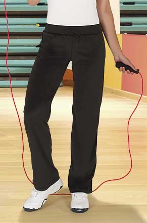 Piernas de mujer con pantalones deportivos negros y zapatillas blancas sujetando una comba roja en un gimnasio.