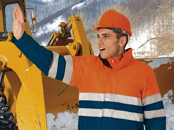 Operario con casco y chaqueta reflectante señalando junto a una pala cargadora en un entorno nevado