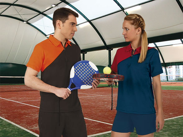 Hombre y mujer con palas de pádel intercambiando una pelota en una pista cubierta