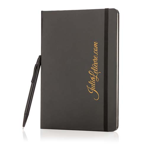 cuaderno negro de tapa dura con banda elástica y bolígrafo negro apoyado junto al lomo, con texto JulioLeiteiro.com en la portada