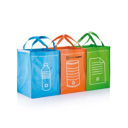 Tres bolsas reutilizables de colores (azul, naranja y verde) con iconos de botella, lata y papel para reciclaje